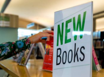 This shot shows a closeup on a woman's hand as she selects a book at a public library.